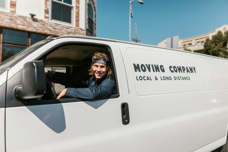 Portrait of a smiling moving company driver in a van on a sunny day outdoors.