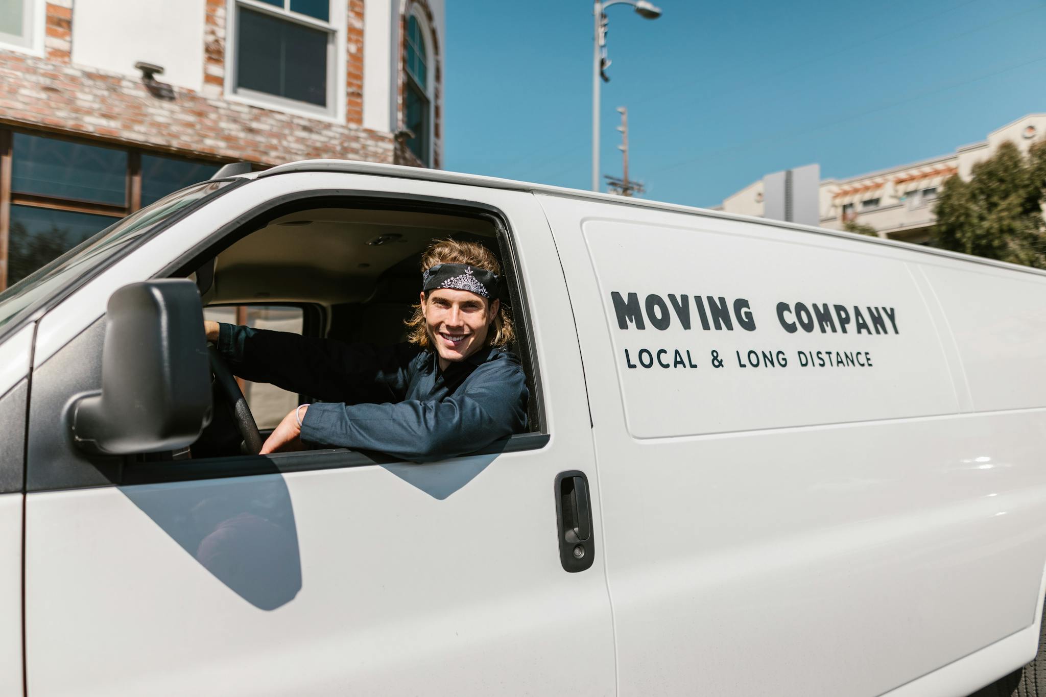 Portrait of a smiling moving company driver in a van on a sunny day outdoors.