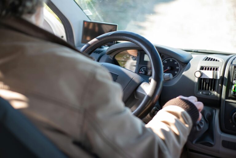 Senior man driving a van through a sunny day in Portugal, showcasing safety and leisure travel.